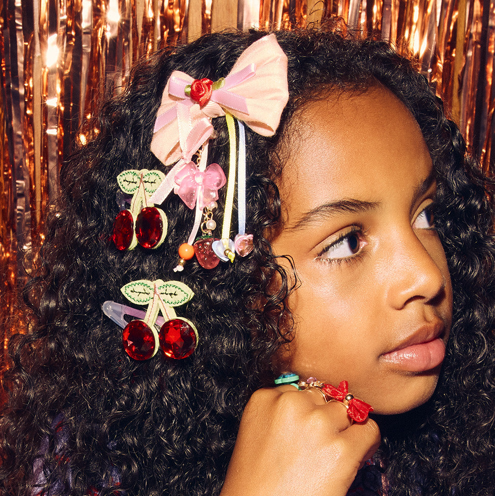 Young girl with decorative hair accessories and colorful jewelry against a glittery background