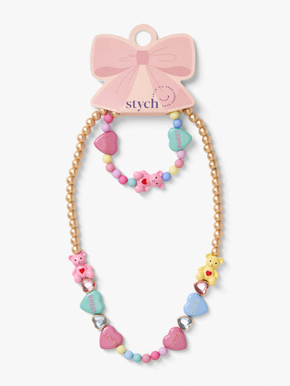 Stych Girls's matching necklace and bracelet set, with pastel colour teddy bear and heart shapes, heart gems and colour beads, set on a gold tone beaded chain. Elasticated.