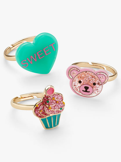 Stych Girls Pack of 3 colourful ring set with sparkly cupcake, teddy bear face and heart 'sweet' slogan decorative designs. Rings adjustable 